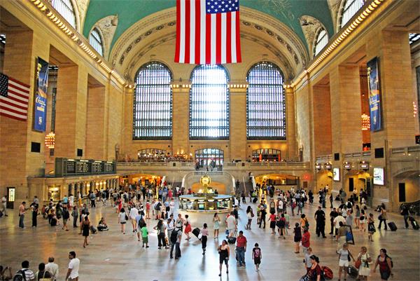 Grand Central Station in New York with a lot of people and an American flag displayed Grand Central Station in New York with a lot of people and an American flag displayed